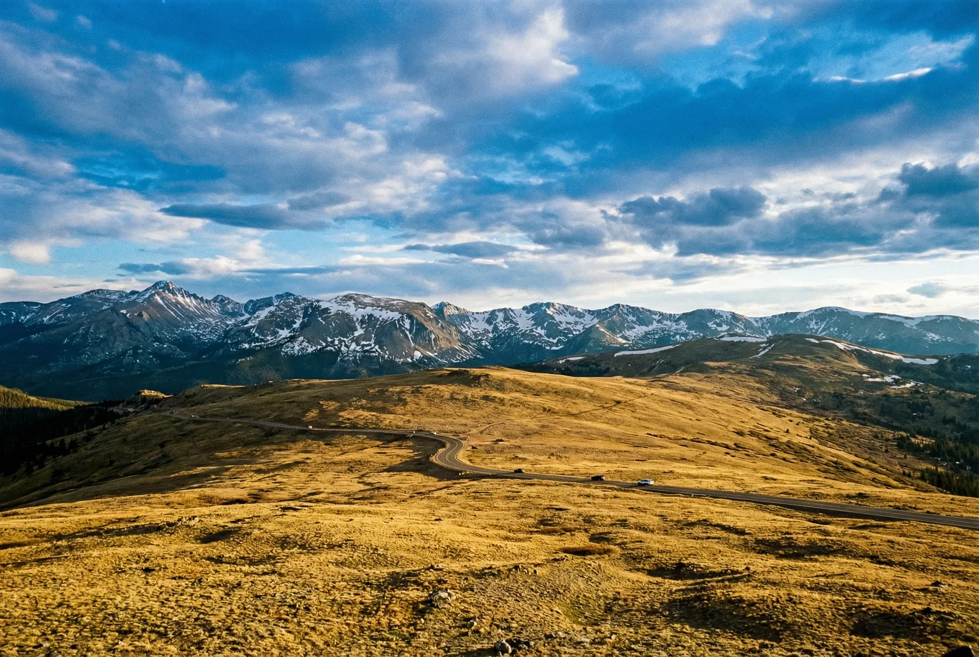 Trail Ridge Road winding across alpine tundra with snow-capped Rocky Mountain peaks