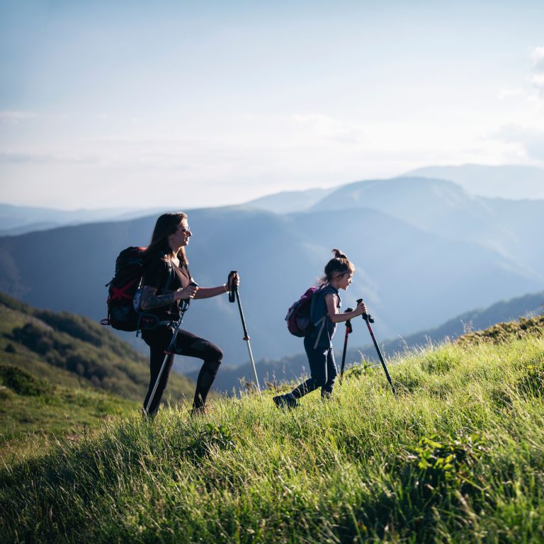 Two people hiking in the Colorado mountains wearing layered clothing and backpacks—what to pack for a Colorado vacation.